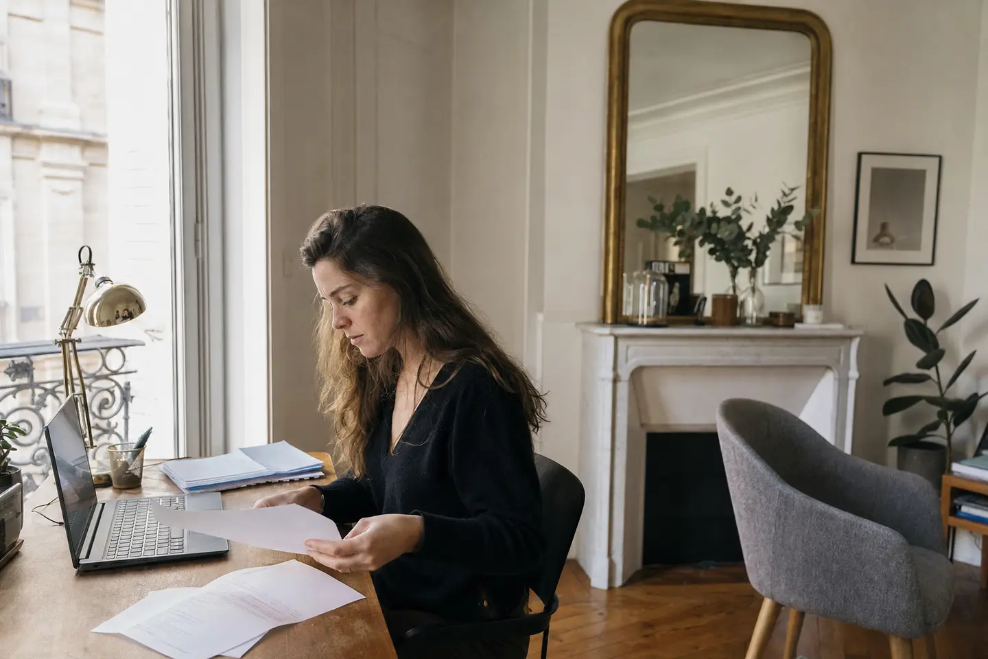 Indépendante travaillant à un bureau aménagé dans son appartement, illustrant l'assurance d'une activité professionnelle à domicile