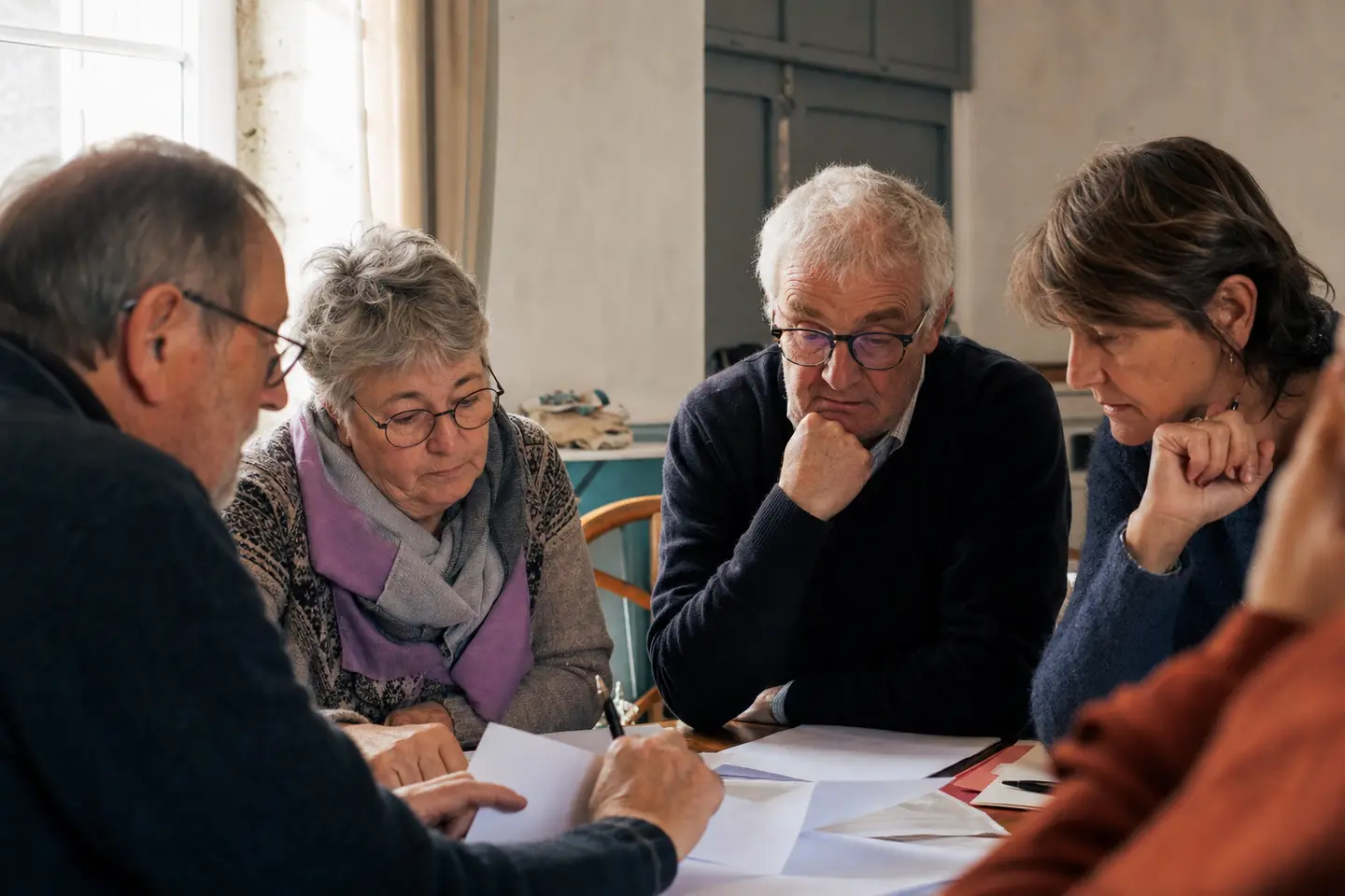 Bénévoles d'une association loi 1901 examinant des documents d'assurance autour d'une table dans une salle communale