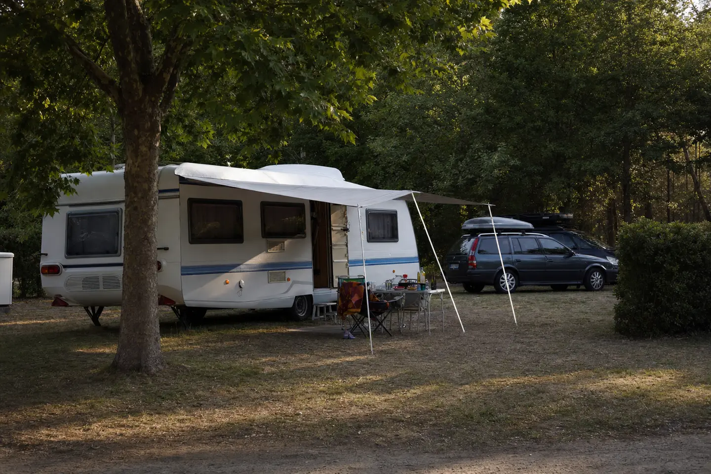 Caravane familiale attelée à un break, installée sur un emplacement ombragé de camping en France