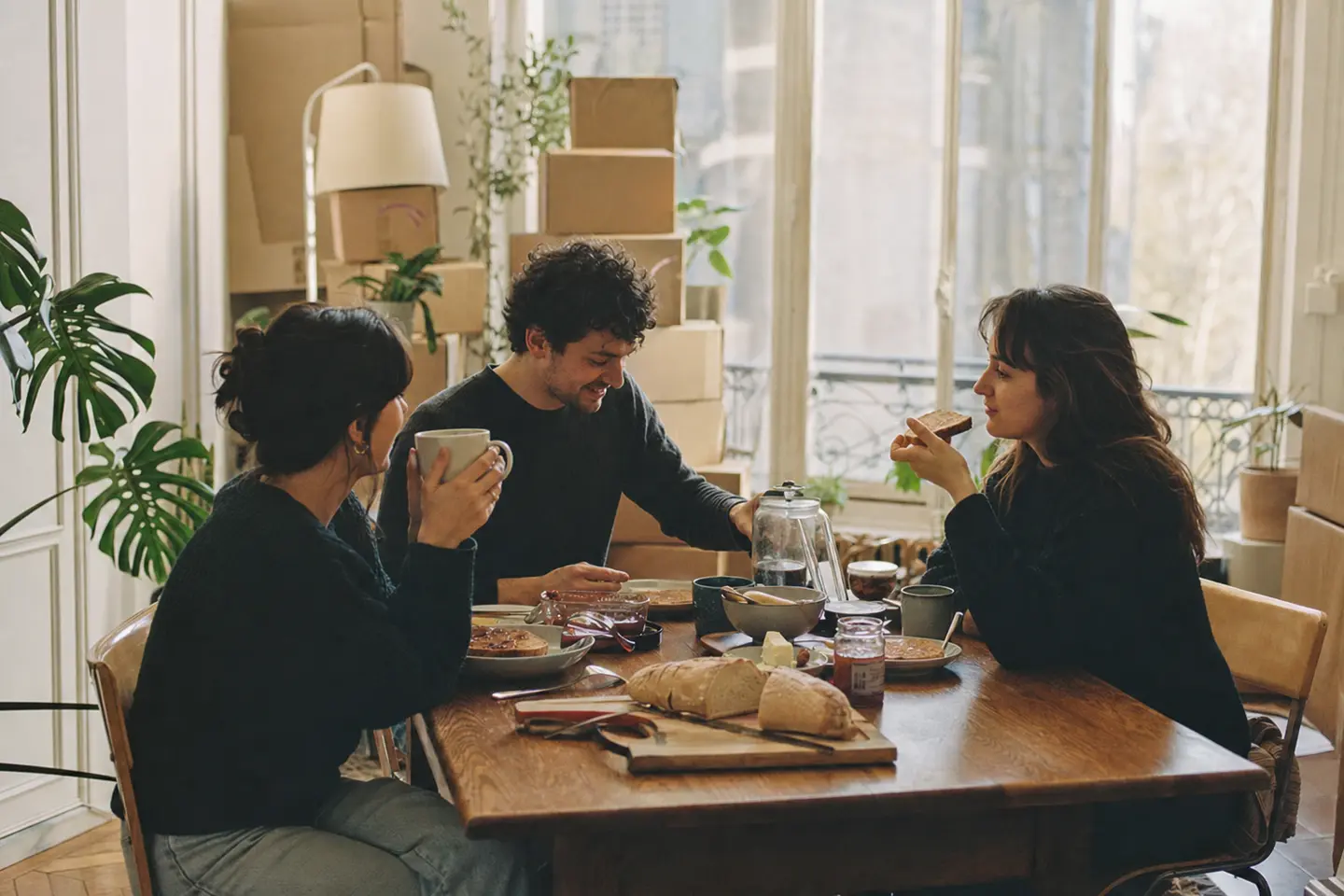 Trois colocataires partageant un petit-déjeuner dans la cuisine lumineuse de leur appartement en colocation