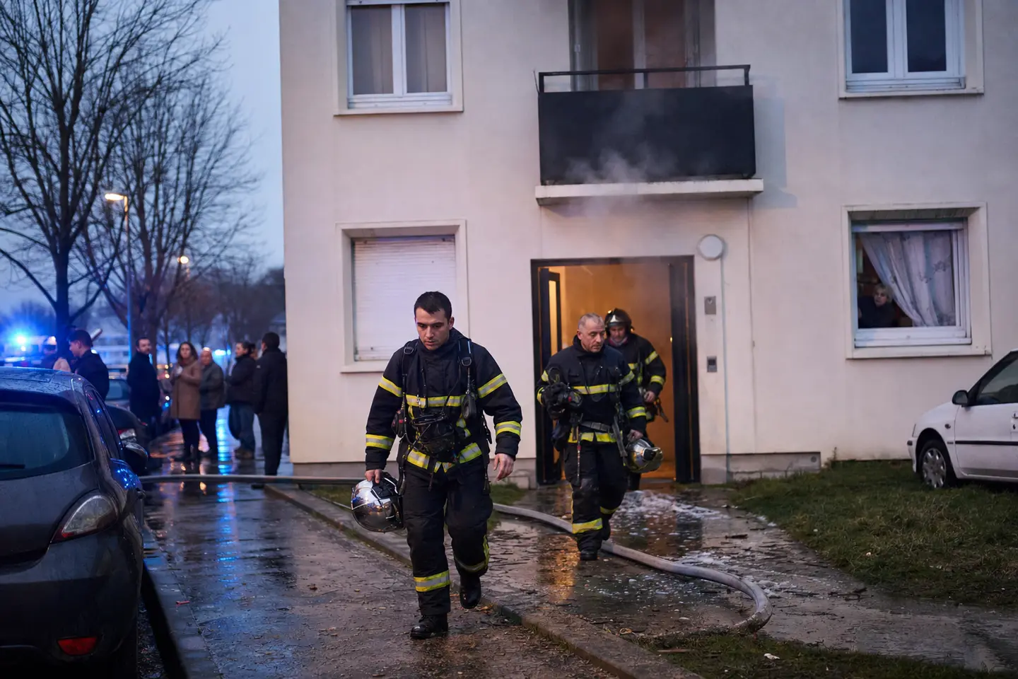 Des sapeurs-pompiers quittent un immeuble d'habitation après avoir maîtrisé un incendie d'appartement