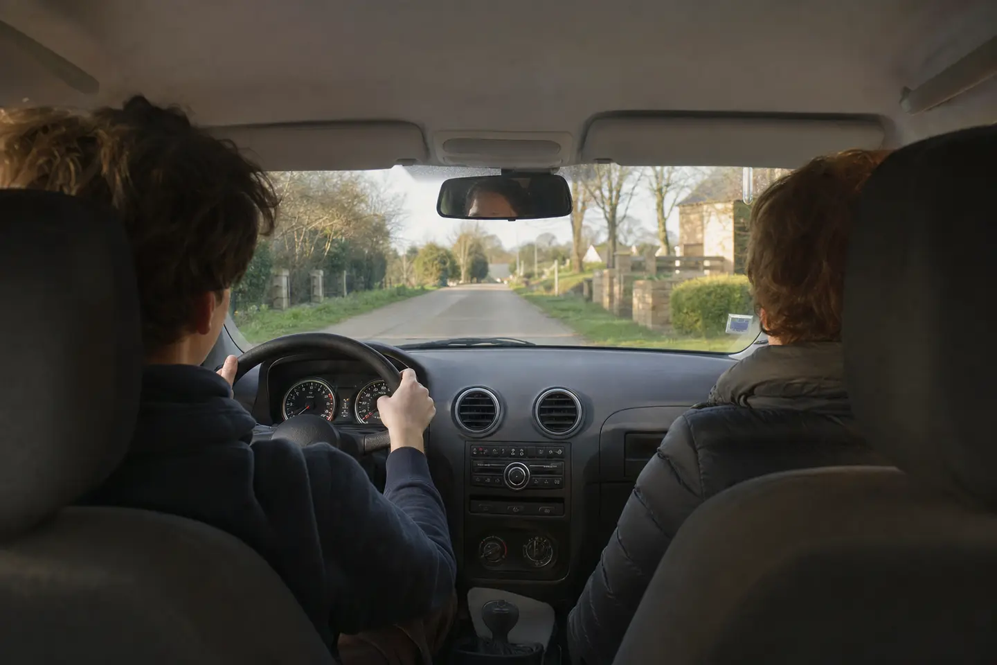 Jeune conducteur en conduite accompagnée au volant d'une citadine, accompagnateur assis à ses côtés sur une route de campagne française