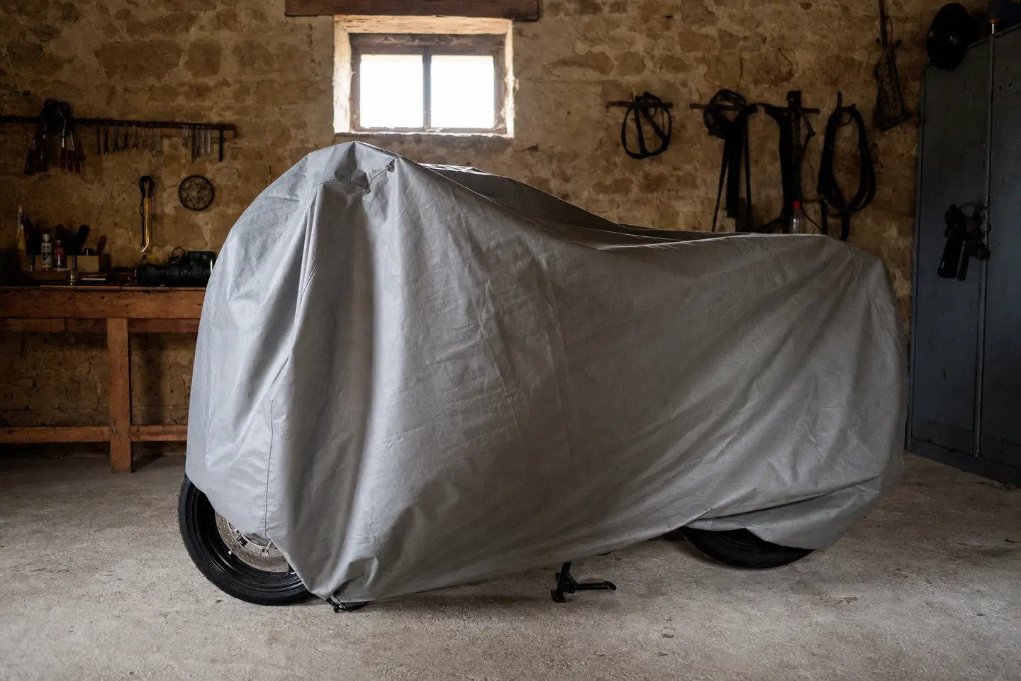 Moto remisée sous une housse de protection dans un garage privé pendant l'hivernage