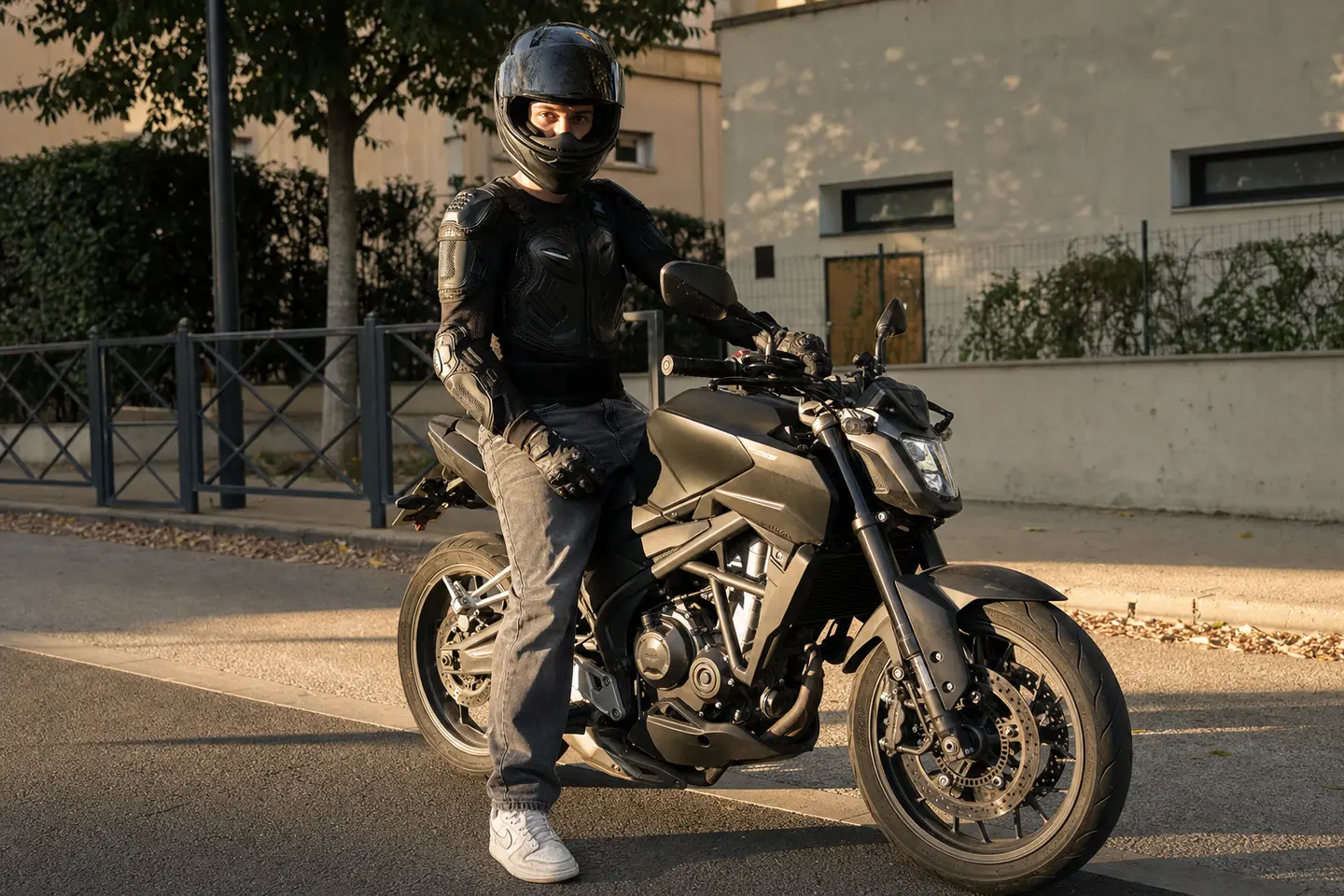 Jeune motard équipé au guidon de sa première moto A2 devant une moto-école française