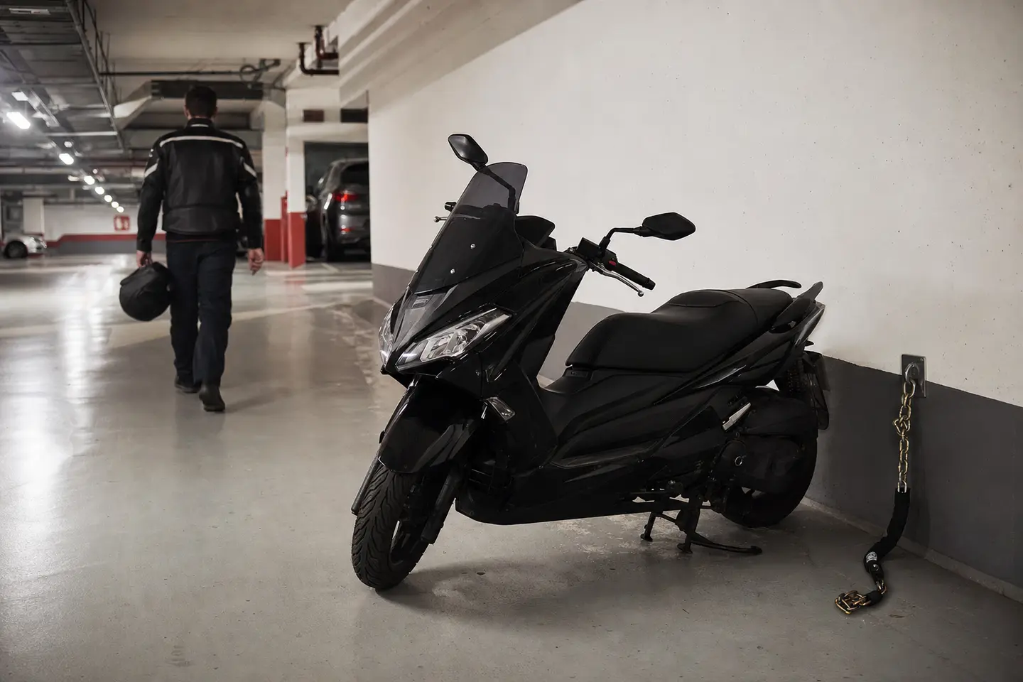 Maxi-scooter attaché avec une chaîne antivol à un point fixe dans un parking souterrain parisien