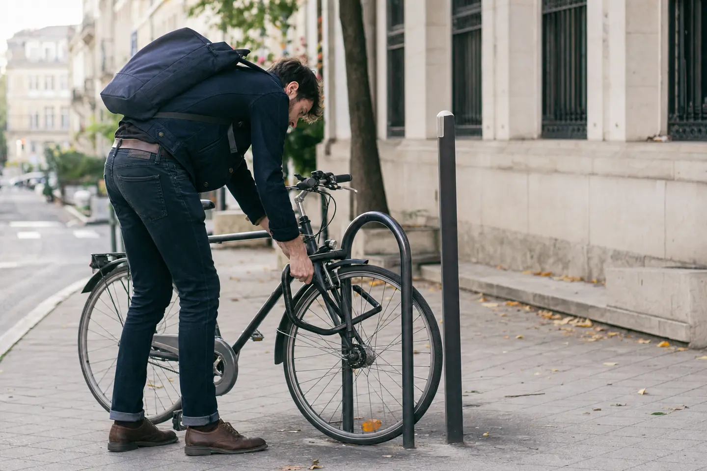 Cycliste attachant le cadre de son vélo à un arceau avec un antivol en U certifié dans une rue française