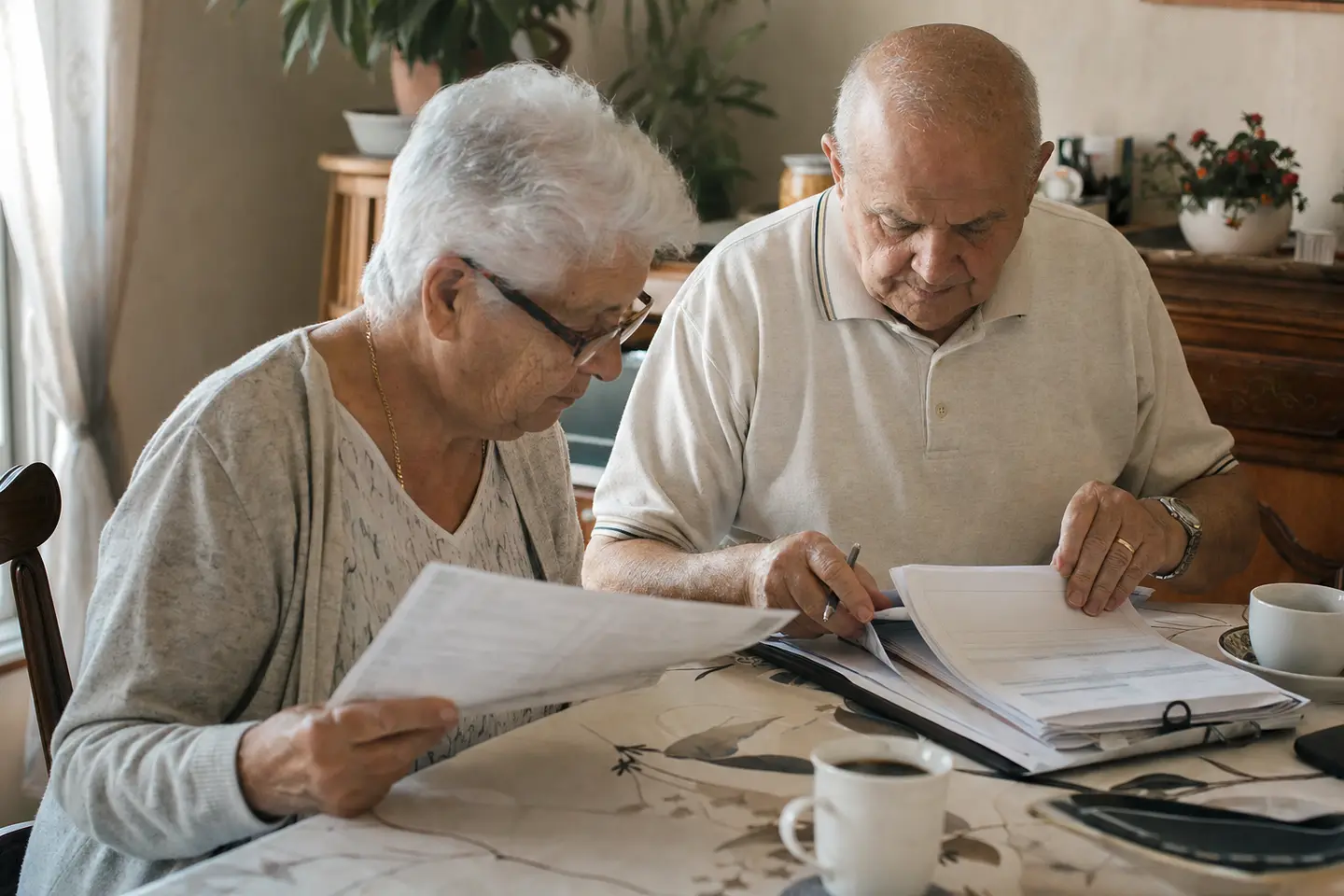 Un couple de retraités examine ses relevés de pension pour vérifier son droit à la complémentaire santé solidaire.