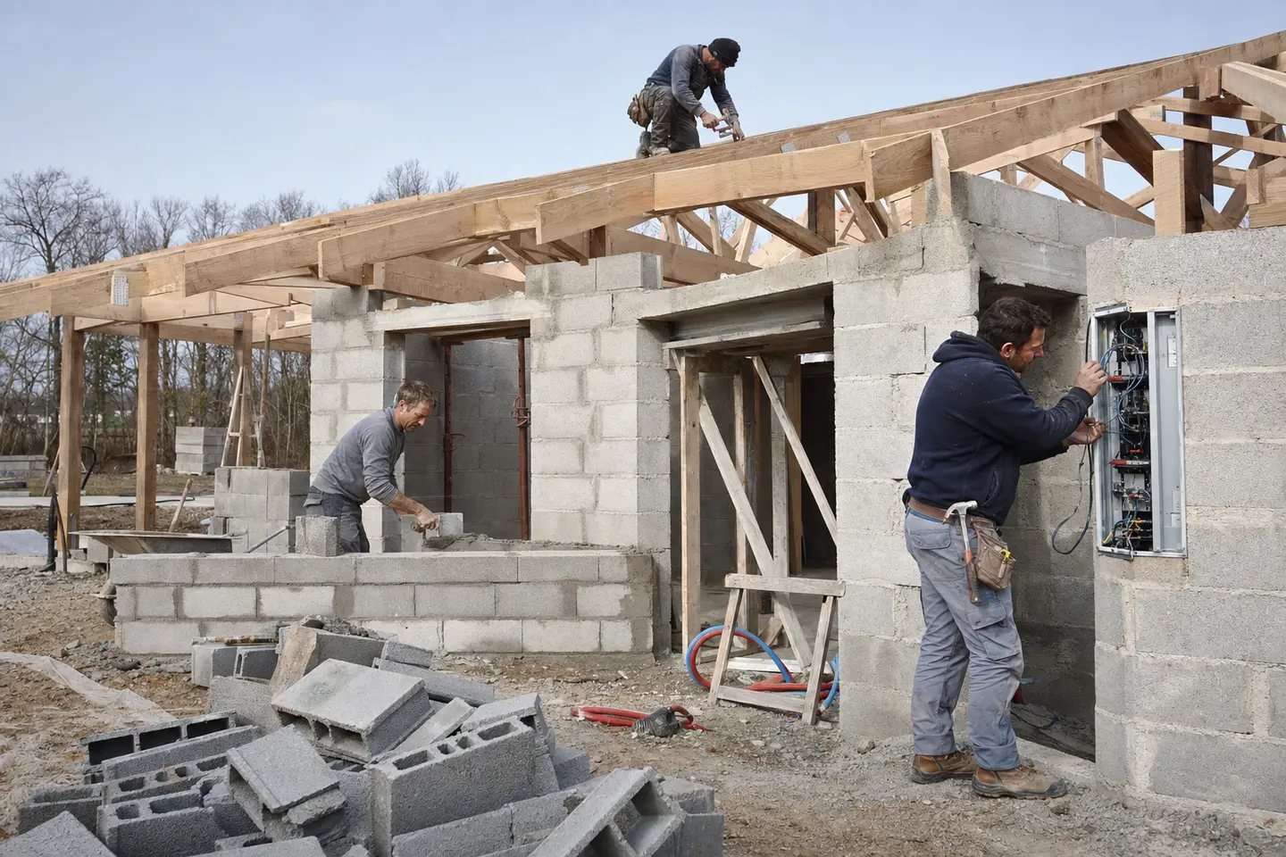 Chantier de maison avec plusieurs corps de métier au travail, tous concernés par l'obligation d'assurance décennale