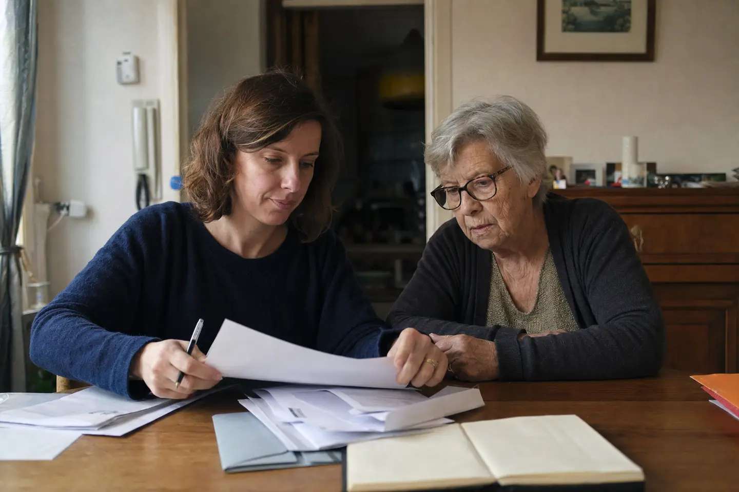 Deux proches classant sur la table familiale les documents administratifs nécessaires aux démarches après un décès