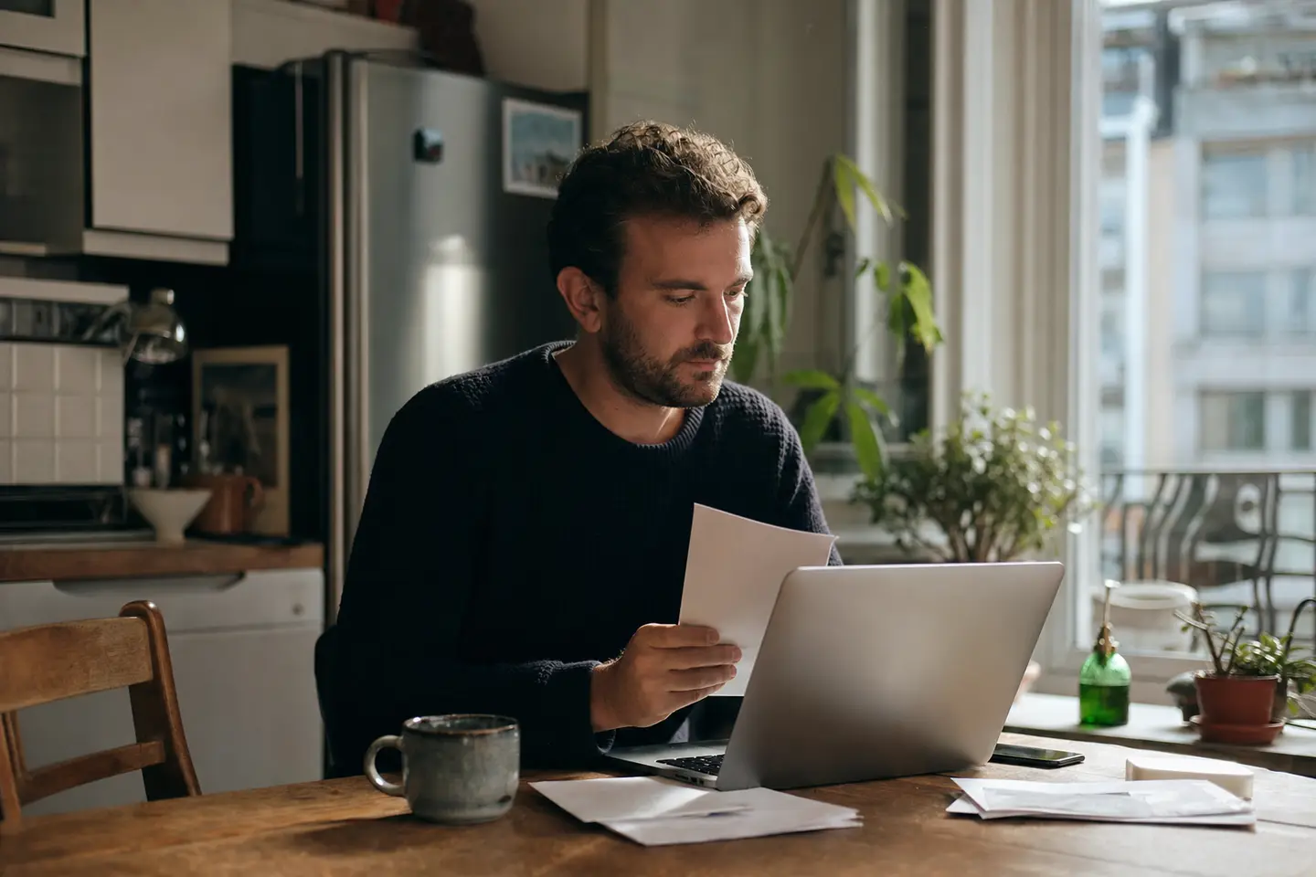 Salarié examinant à domicile un courrier de mutuelle et son bulletin de salaire pour préparer une demande de dispense