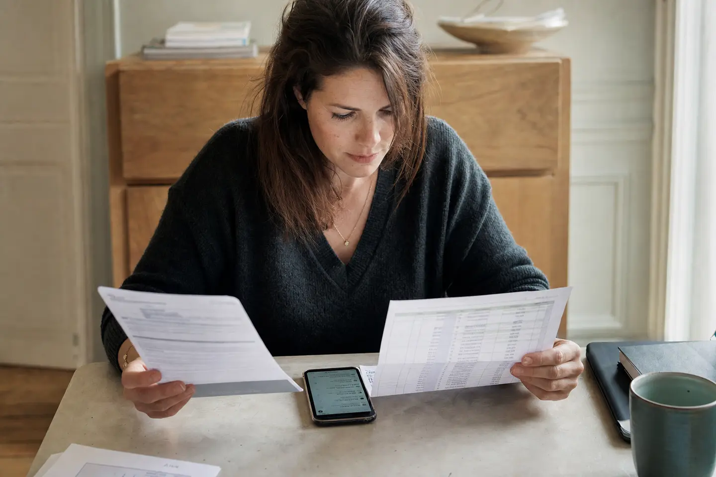Une épargnante compare un livret d'épargne et un relevé d'assurance vie posés côte à côte sur son bureau