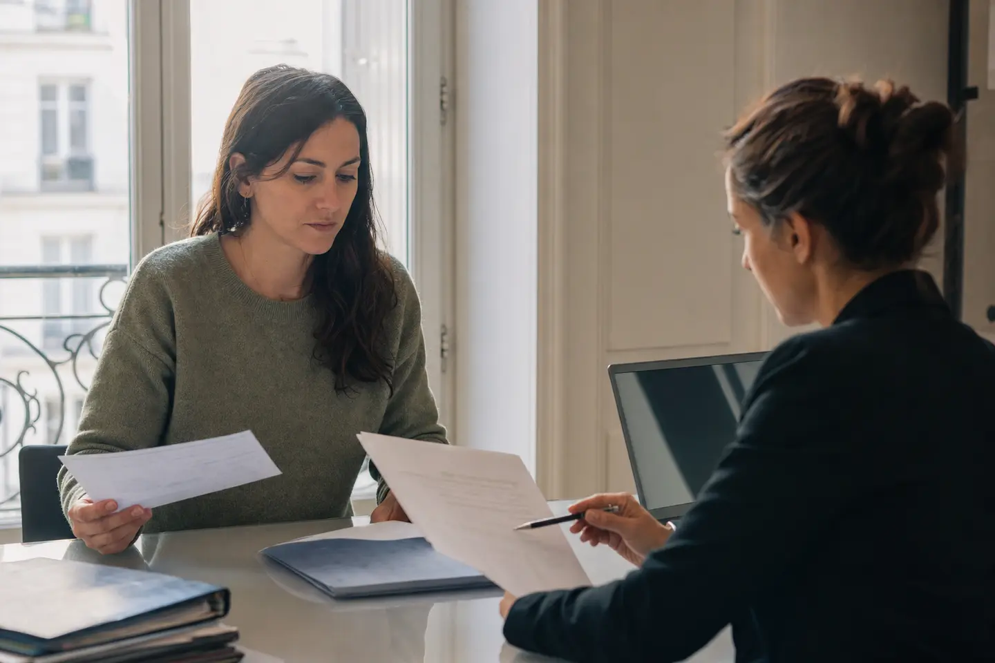 Une salariée examine son contrat de travail et un bulletin de paie avec un conseiller juridique dans un bureau