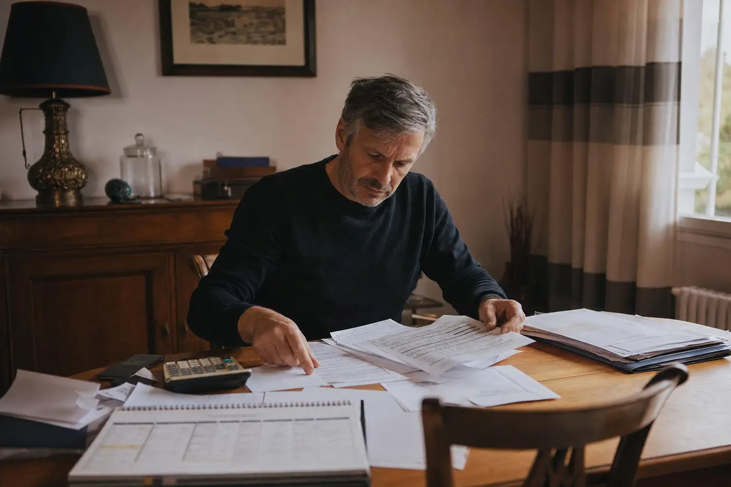Un emprunteur compare les dates de résiliation de son assurance de prêt à partir de ses documents de crédit