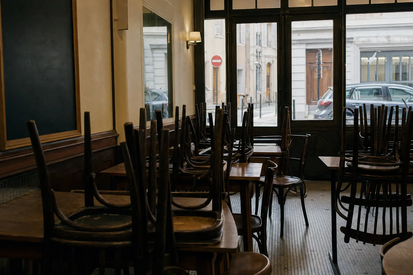 Salle de restaurant vide, chaises retournées sur les tables et panneau fermé, sans aucun dégât matériel apparent