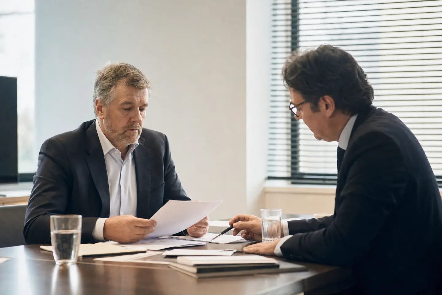 Dirigeant d'entreprise examinant des documents avec un avocat dans une salle de réunion, illustration d'une mise en cause pour faute de gestion