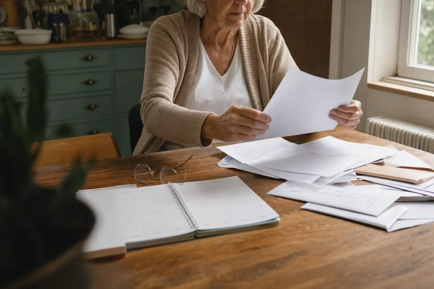 Une assurée prépare le renouvellement de sa complémentaire santé solidaire à sa table, courrier de la caisse et calendrier à portée de main.