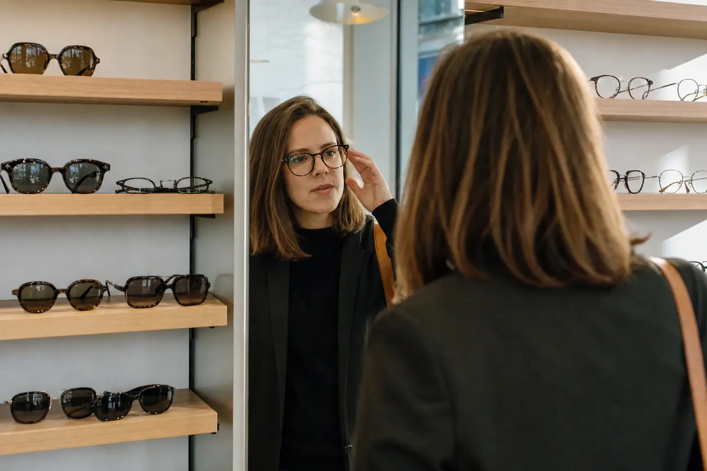 Essayage d'une nouvelle monture de lunettes devant un miroir chez un opticien