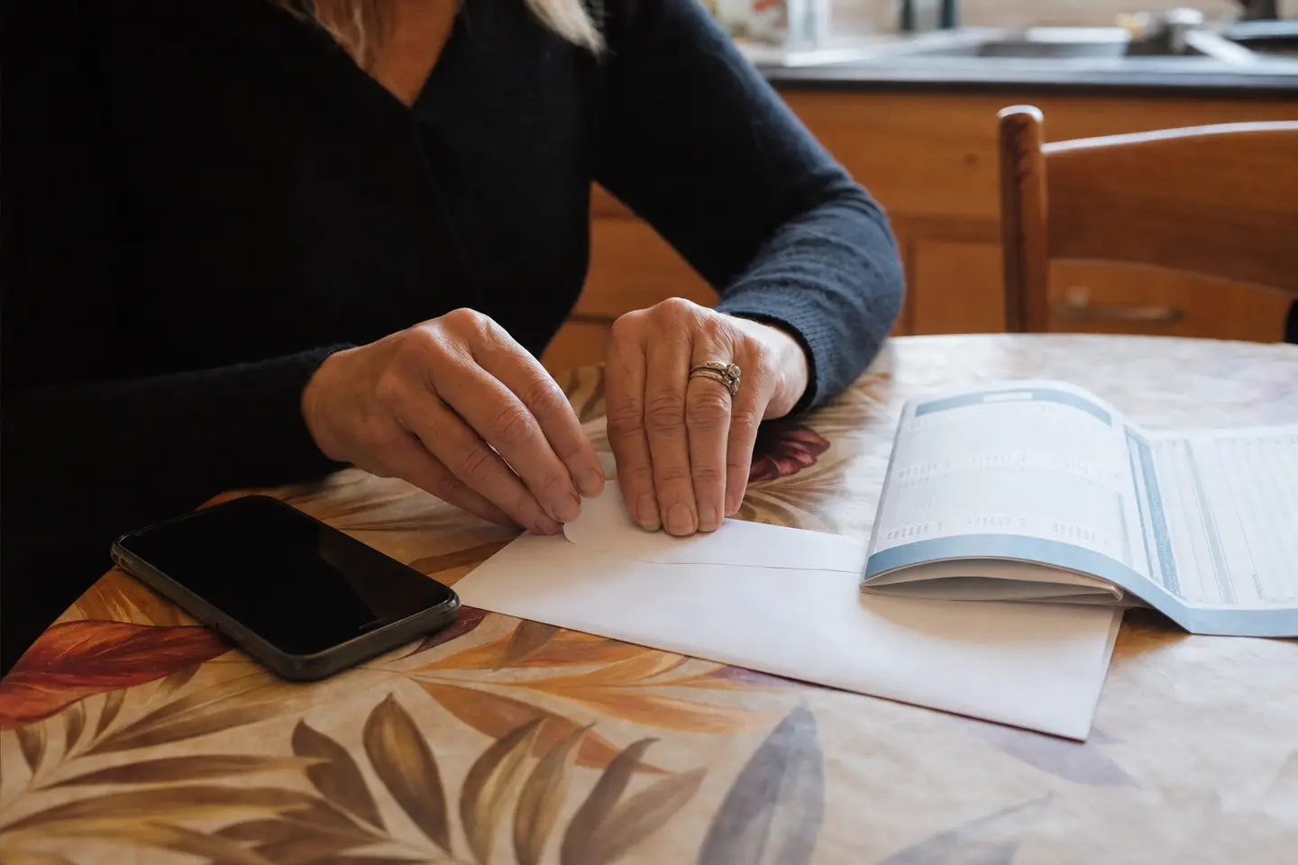Mains cachetant une lettre de résiliation à côté d'un smartphone et d'un relevé bancaire sur une table