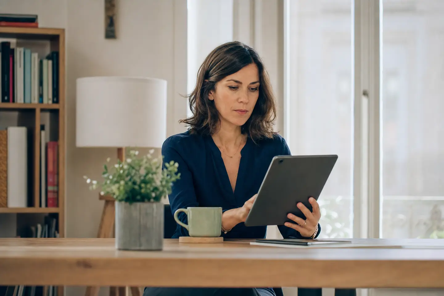 Une épargnante consulte la répartition de ses unités de compte sur une tablette à son bureau