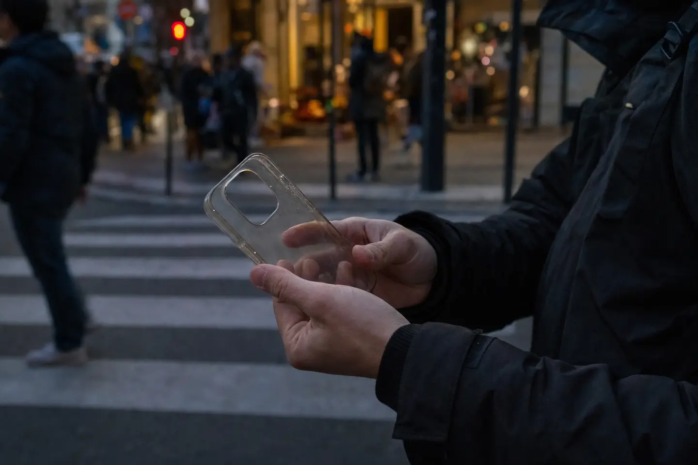 Personne constatant le vol de son téléphone dans une rue passante, étui vide en main